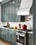 Cozy kitchen with green cabinets, white countertops, and stainless steel appliances.