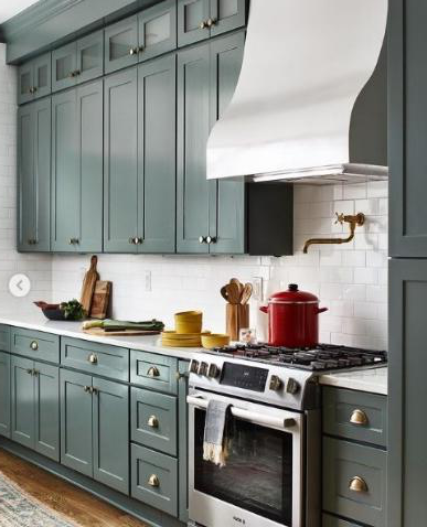 Cozy kitchen with green cabinets, white countertops, and stainless steel appliances.